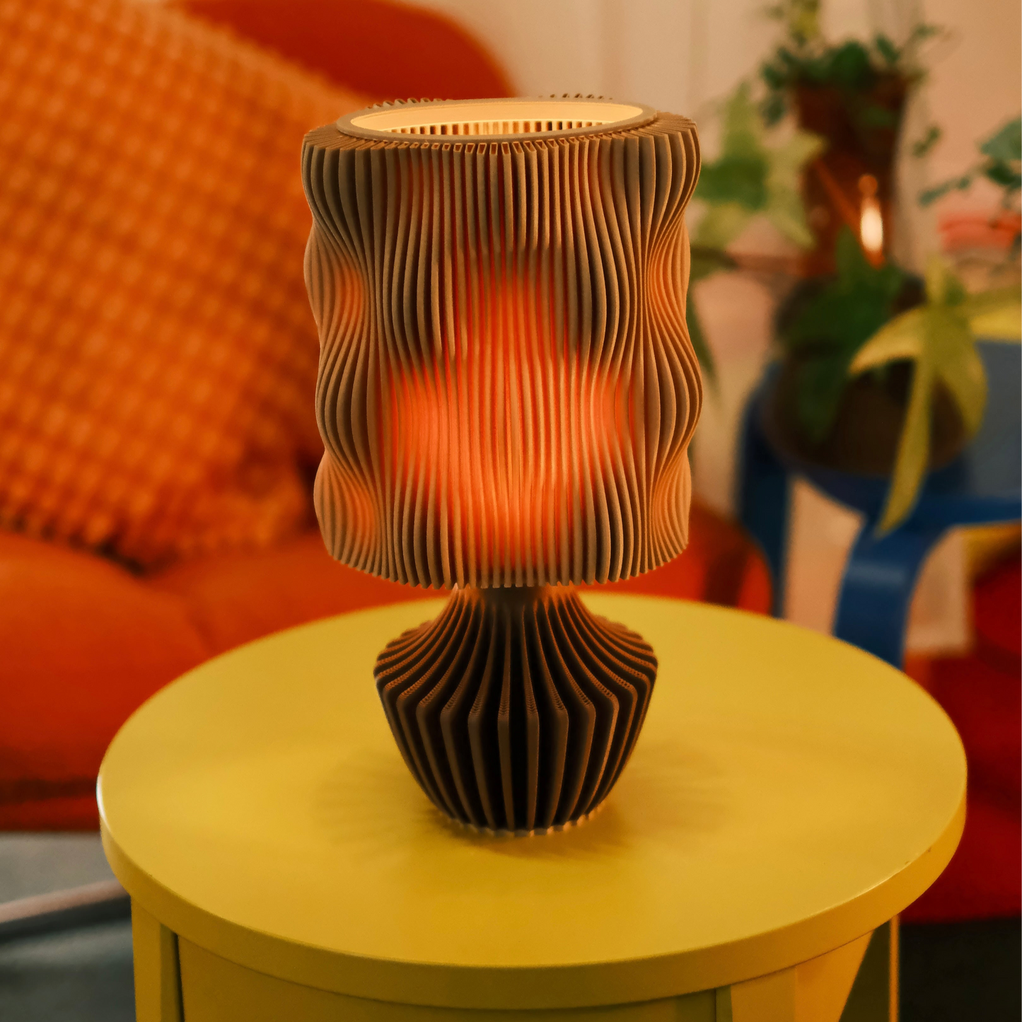 Decorative lamp with wavy design on a yellow table in a cozy room setting.